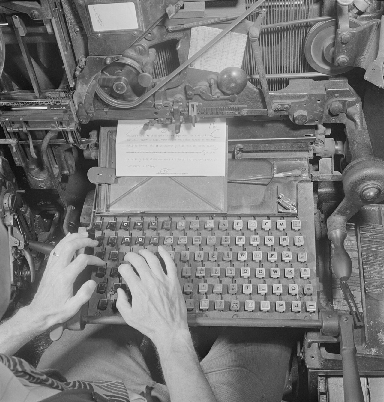Close-up of a letterpress: ink-stained hands setting individual type blocks into a chase.