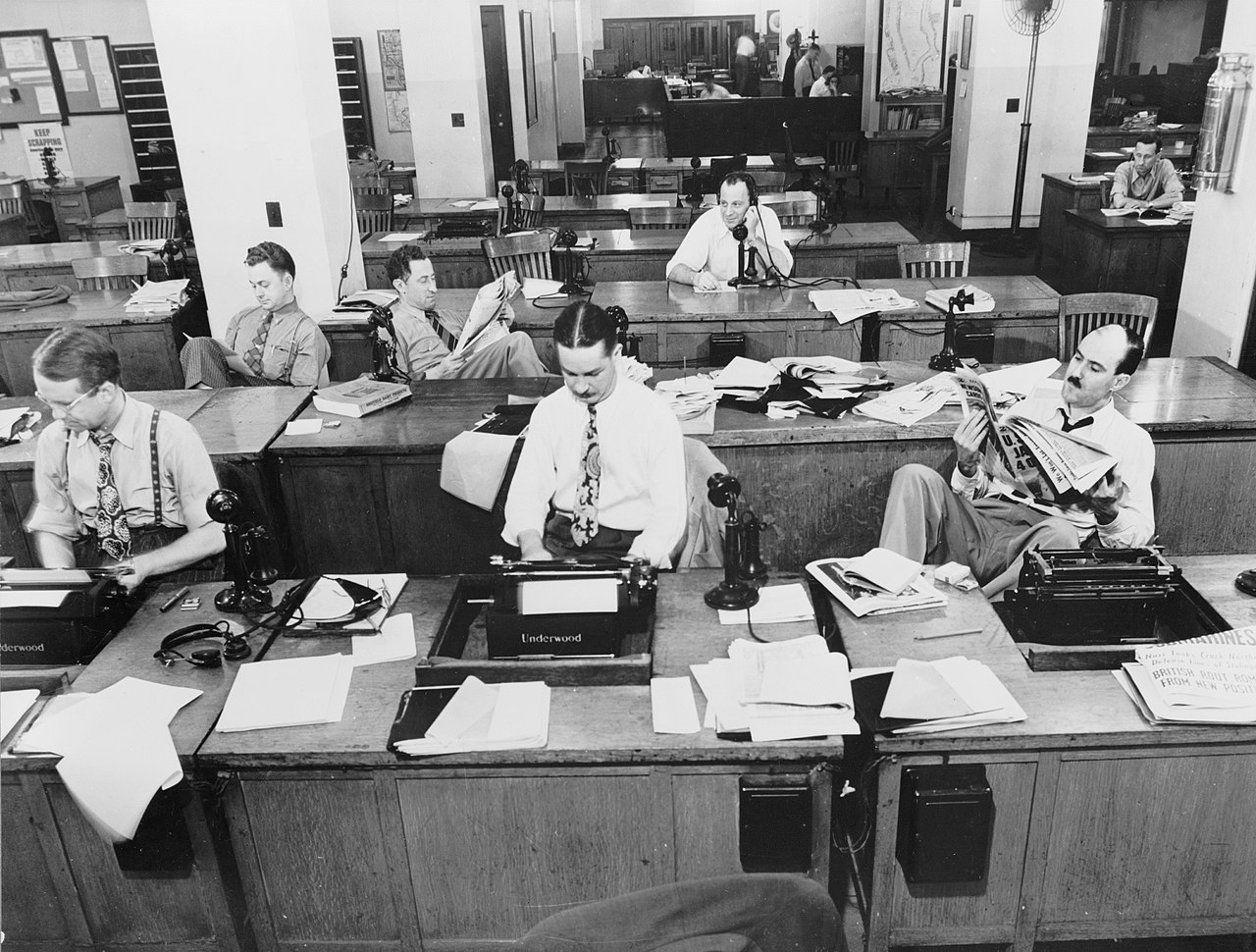 A 1940s newsroom: reporters at desks, papers stacked high, cigarette smoke in the air.
